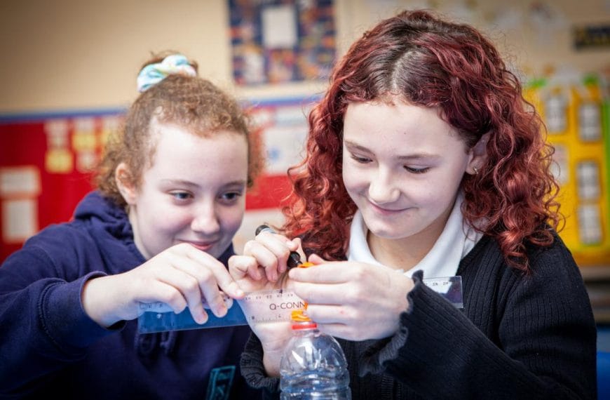 Two school children measure a balloon
