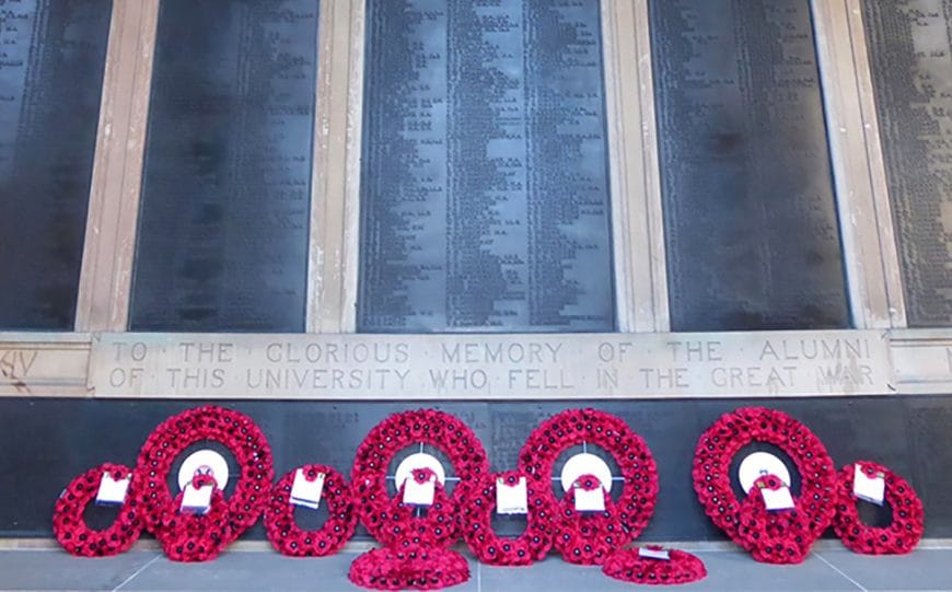Memorial wall at Old College with multiple poppy wreaths laid in front of it.