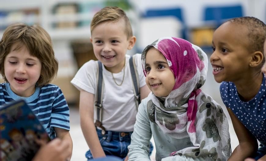School children sat listening to a teacher tell a story