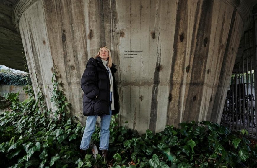Artist Katie Paterson stood next to her artwork on a concrete structure.