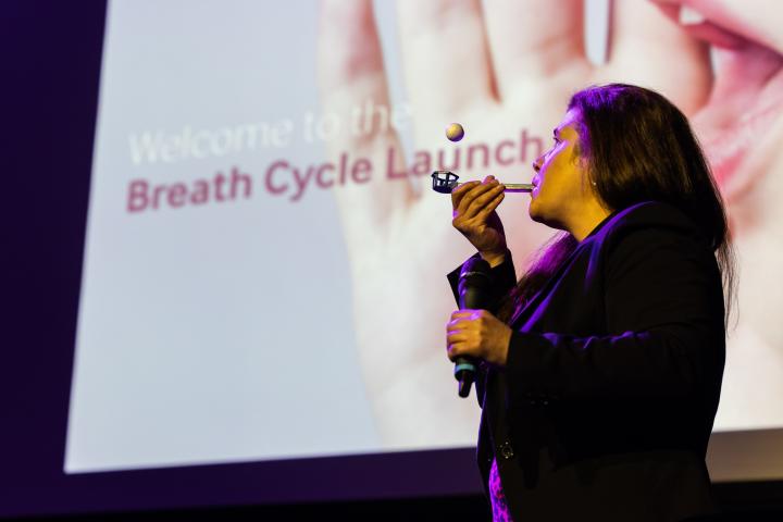 A woman demonstrates breathing techniques at launch of Breath Cycle