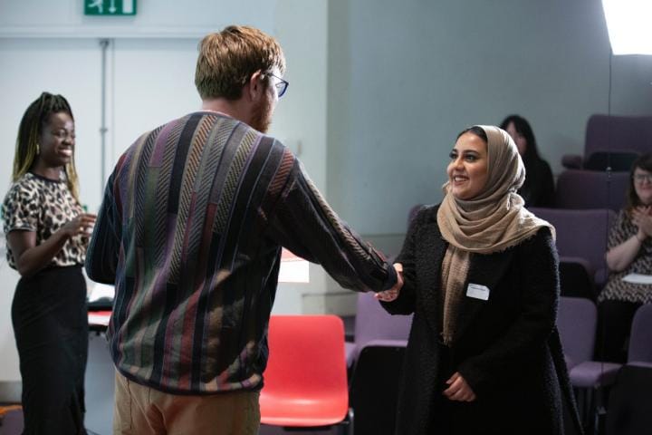 Two people shake hands in greeting