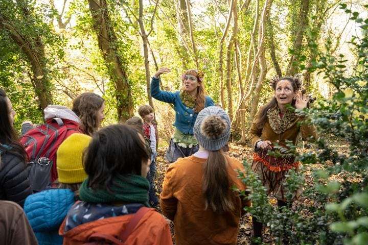 Two performers in the words talking to a group of local schoolchildren and adults.