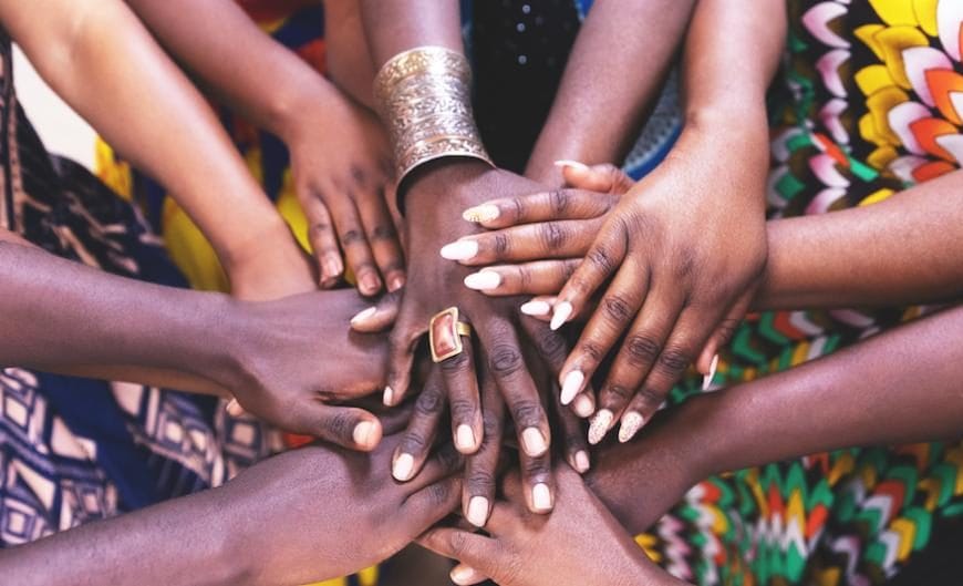 A group of women standing next to each other and joining hands