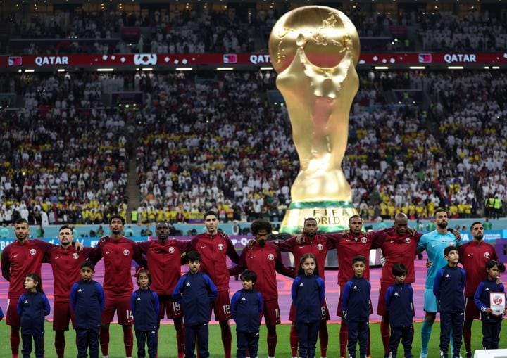 Qatars men's national football team lines up in front of giant replica of World Cup trophy