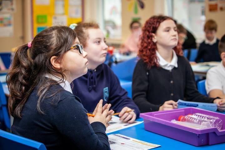 School children sit around a science experiment