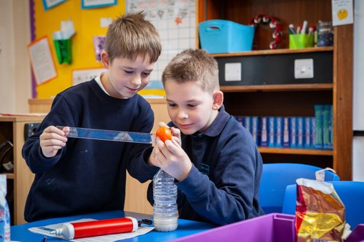 Two school children measure the gas in a ballon