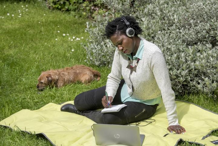 Student at computer outdoors with cute dog