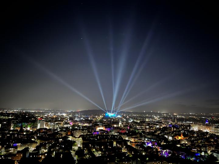 Photo of Edinburgh at night showing the lasers in the sky from the military tattoo performance at the Castle