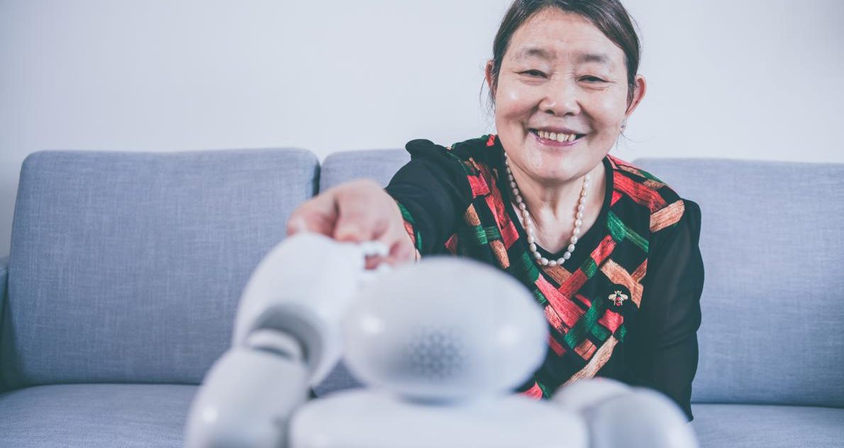 older women interacting with robot at home. Happy and smiling.