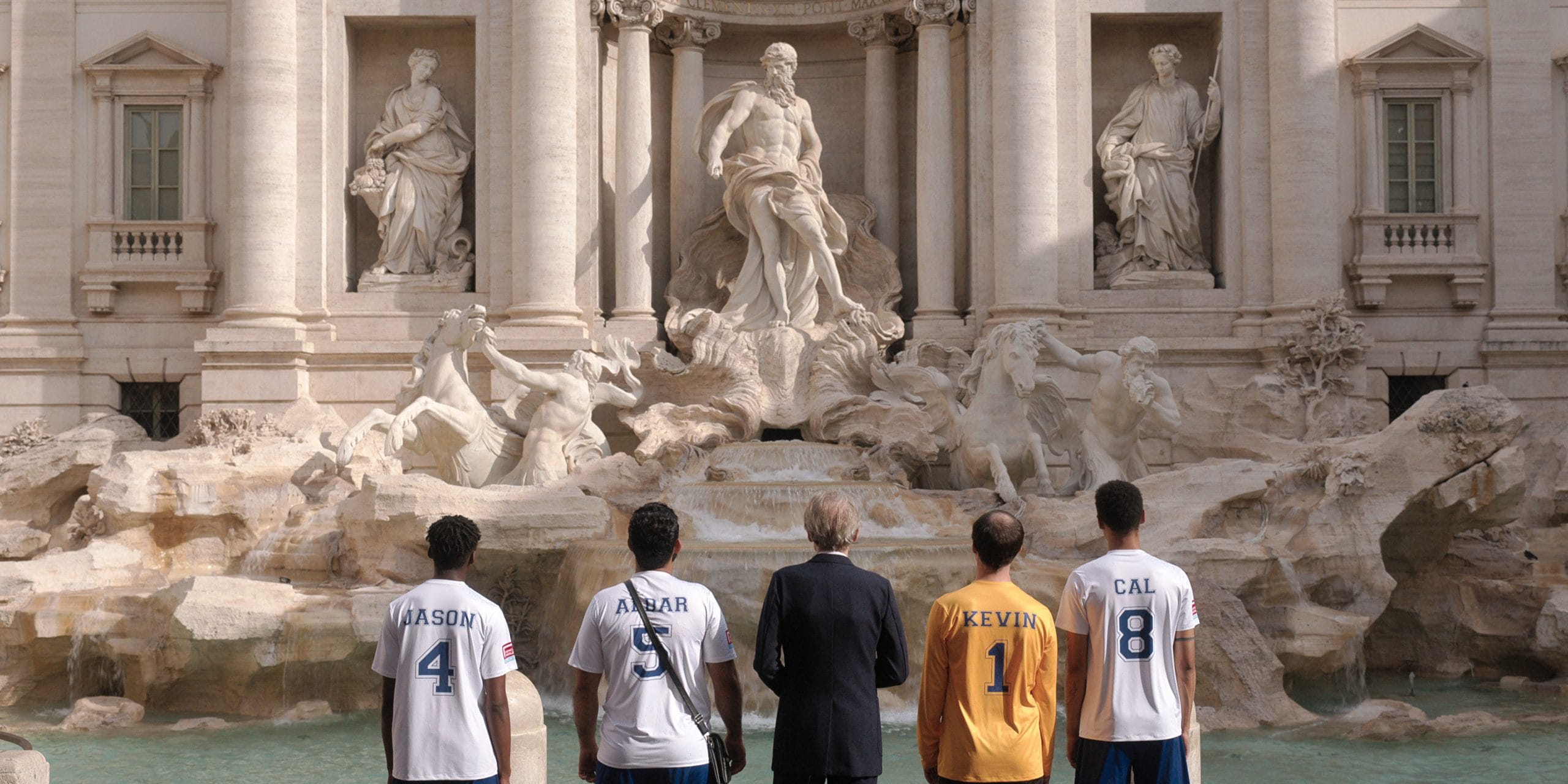 'The Beautiful Game' characters standing in front of the Trevi fountain in Rome.