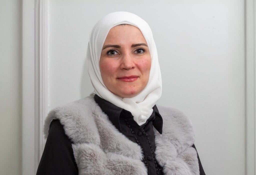 A woman in a headscarf, Nadin Akta, Education Beyond Borders Manager, smiles at the camera.