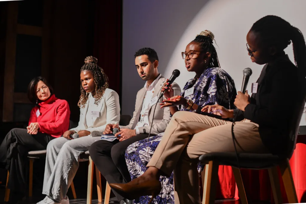 A group of five people take part in an on stage discussion at the Mastercard Foundation President's Meeting.