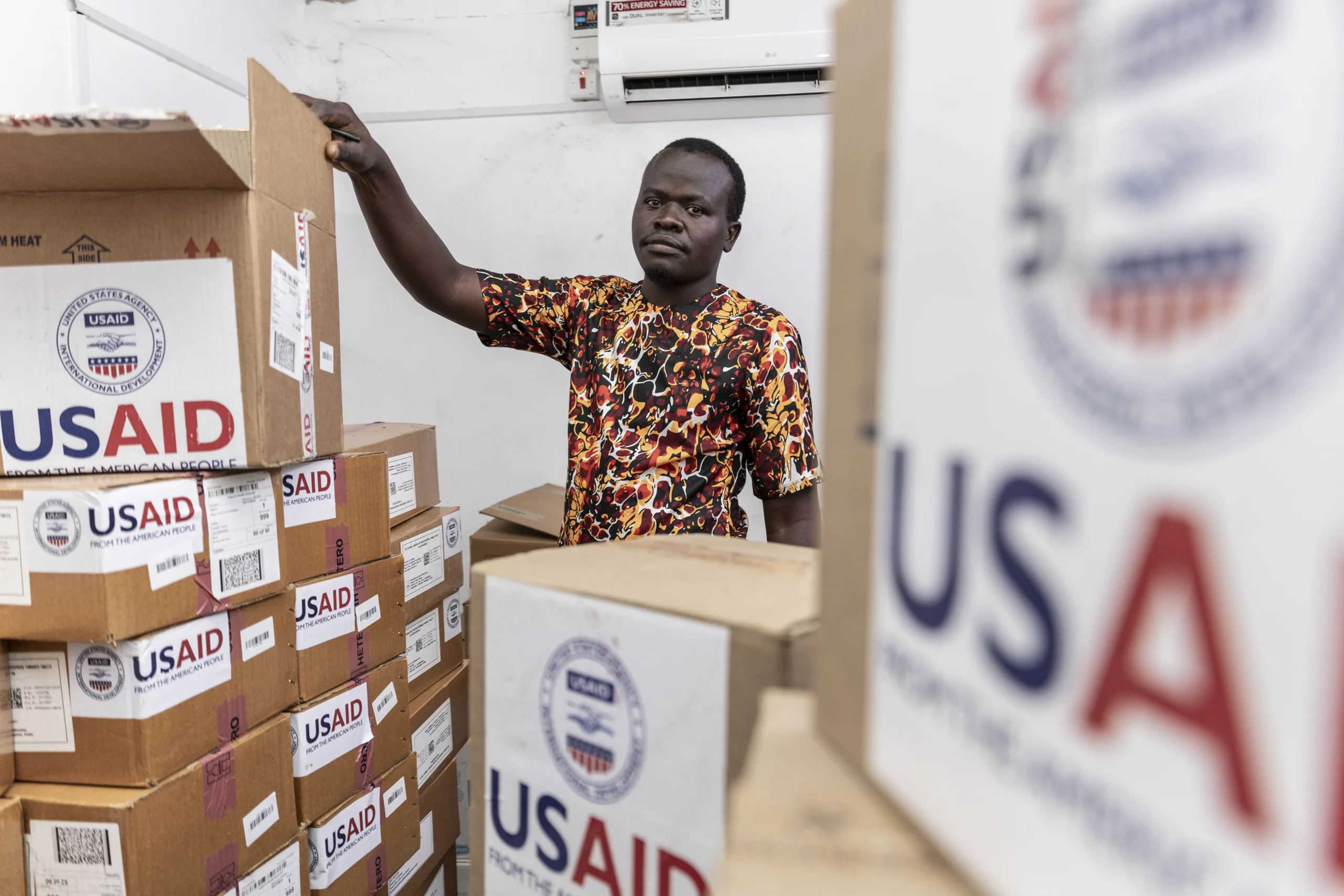 Man surrounded by boxes with USAID on them