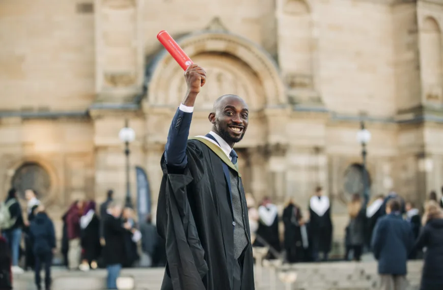 A Nigerian man holds up his graduation scroll outside McEwan Hall at the University of Edinburgh