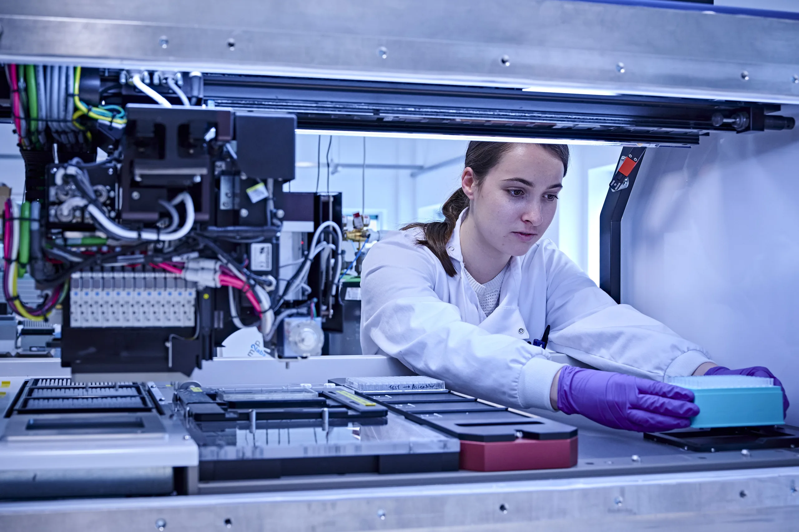 Woman organises experiment in pipetting machine. Engineering biology