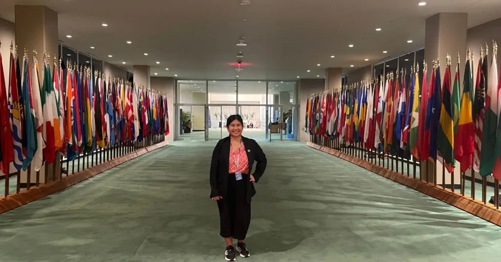 A woman standing in front of flags at the UN