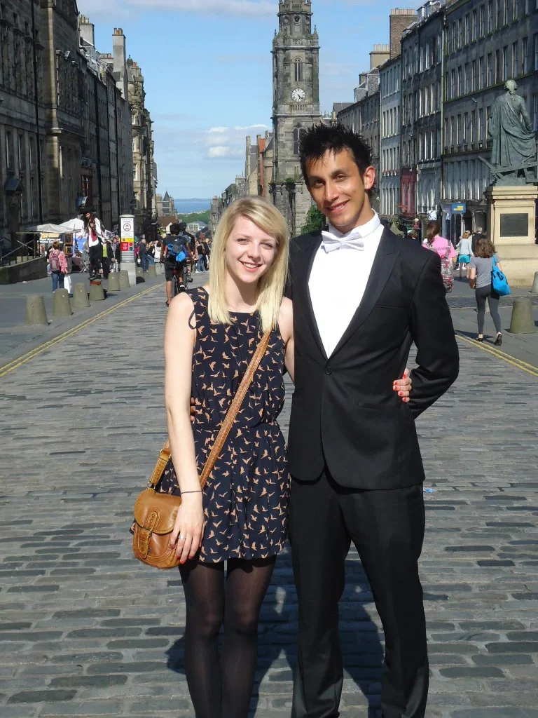 A male graduate standing on the Royal Mile in Edinburgh with his wife.
