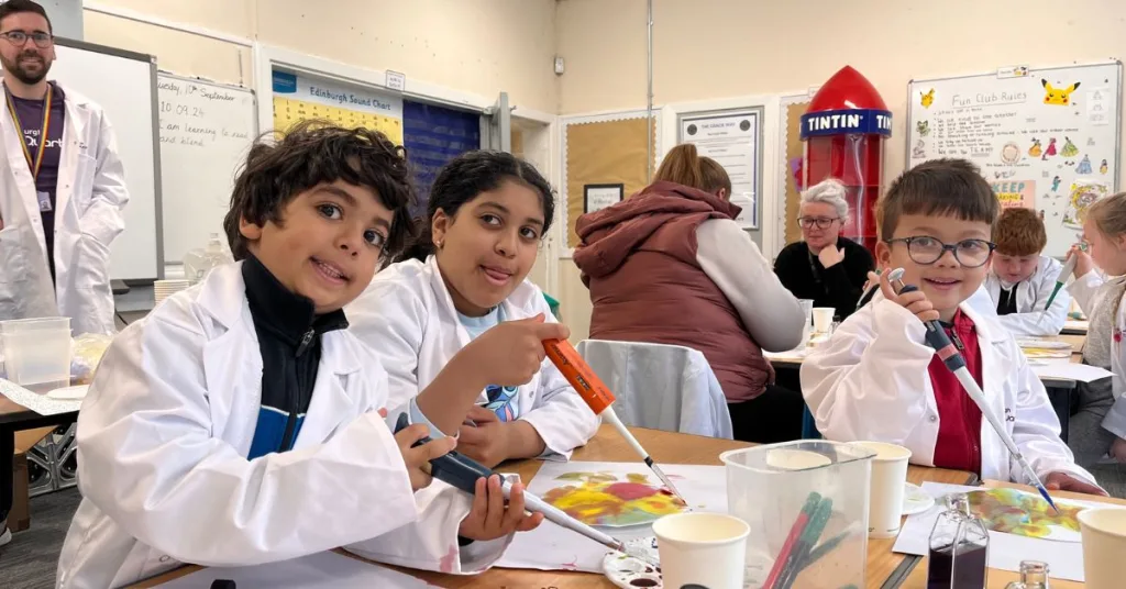 Three children pictured with science tools in a classroom