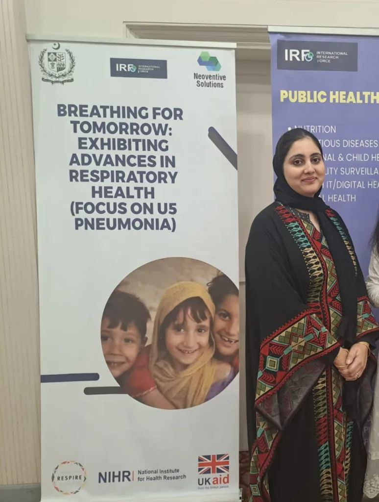 A Pakistani woman standing beside an information board about pneumonia in children