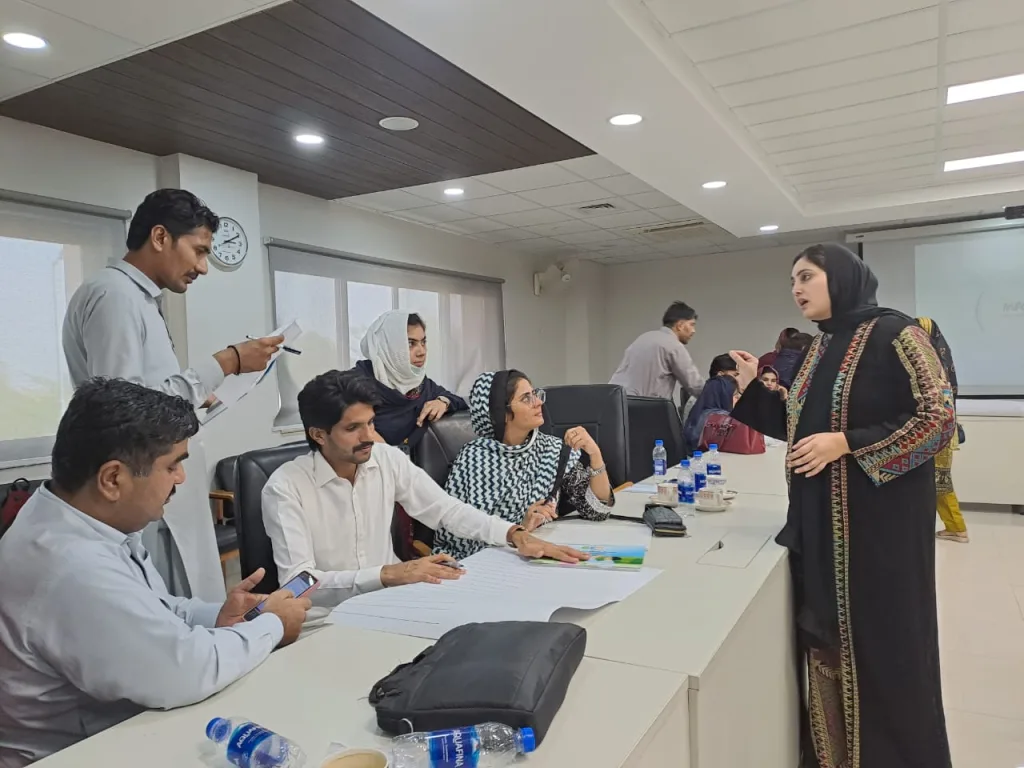 A Pakistani woman at a table with healthworkers 