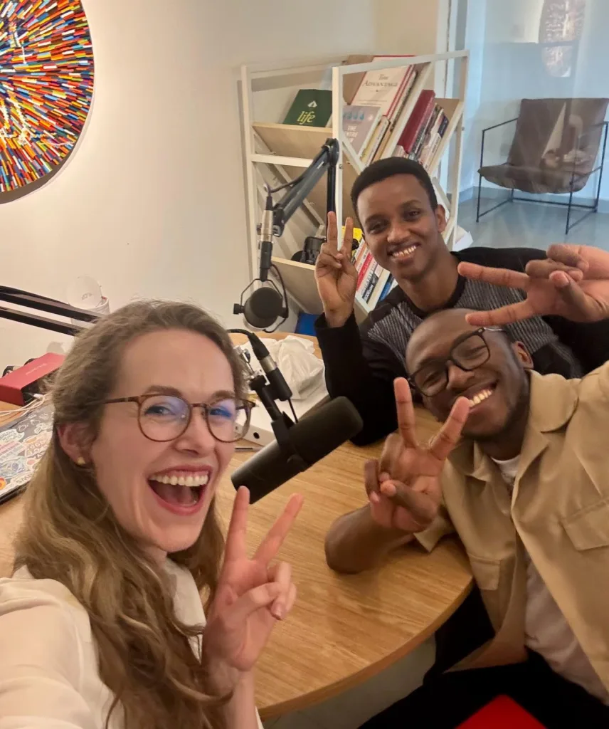 A woman and two men sittting round a table and smiling at the camera