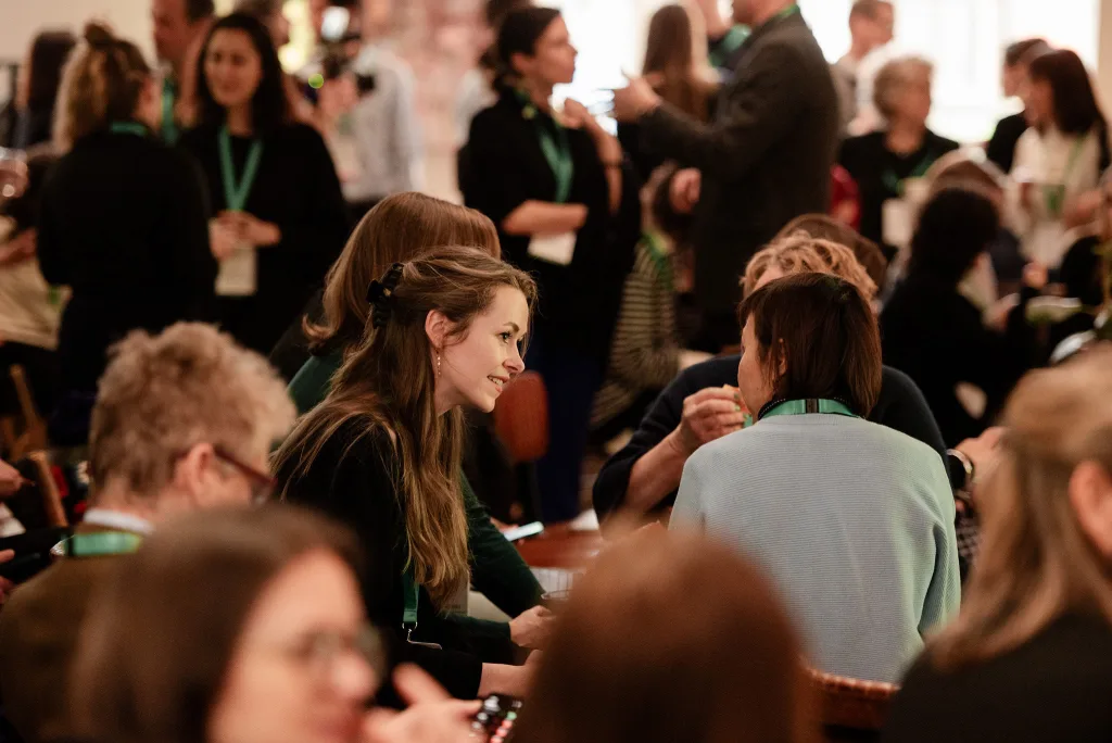 A crowd of people sitting at tables at the Conduit Solutions Lab Refugee Summit in London