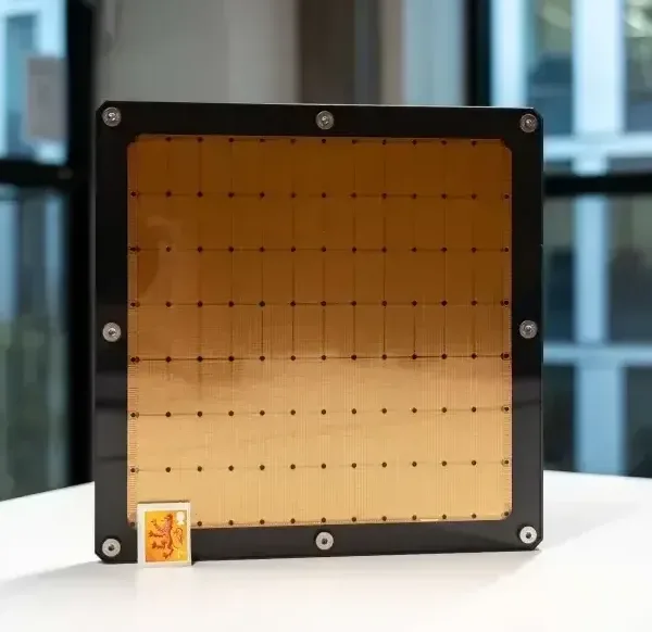 A large macrochip , the size of a dinner plate, with a small stamp in the corner for size comparison.