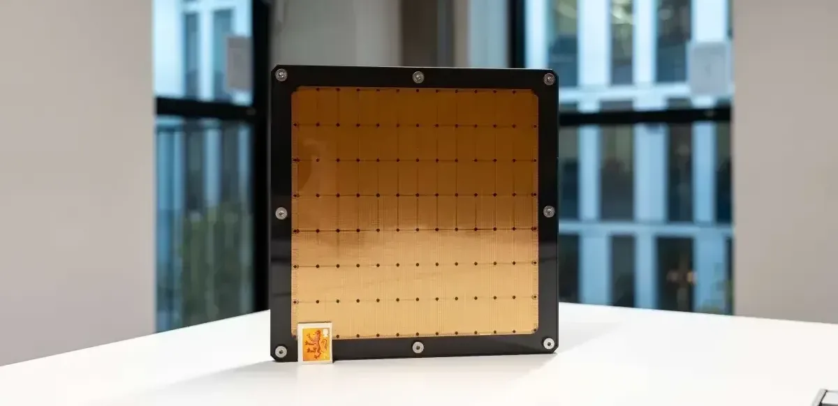 A large macrochip , the size of a dinner plate, with a small stamp in the corner for size comparison.