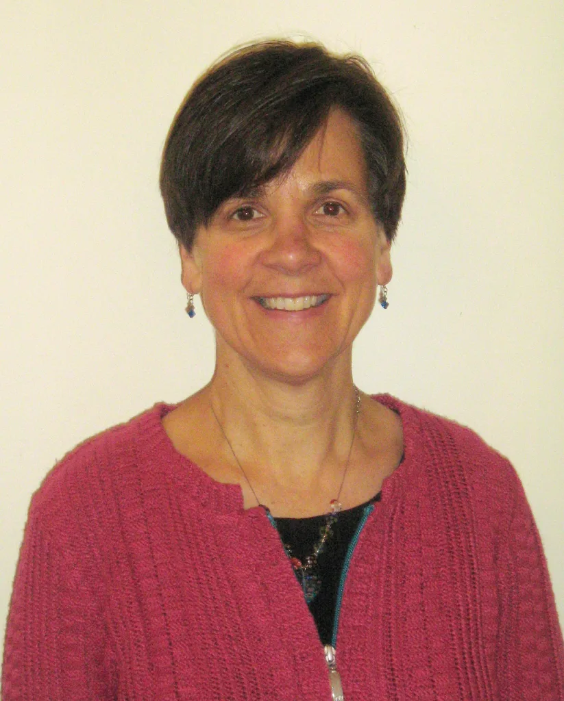 Professor Elizabeth Bomberg facing the camera smiling wearing a pink cardigan. 