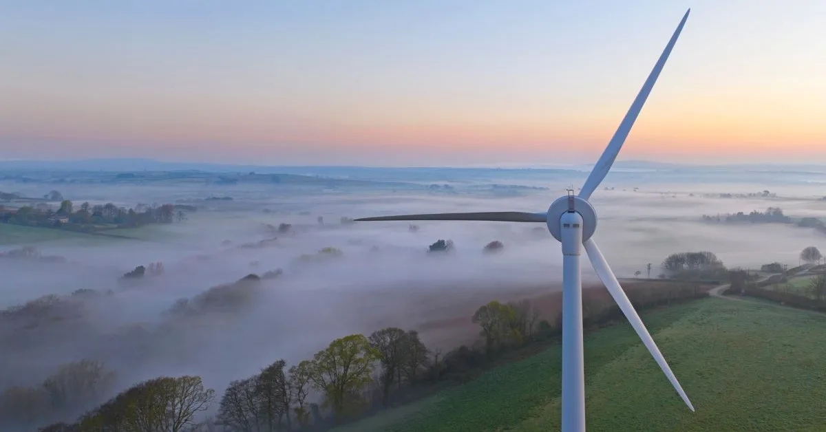 Still wind turbine overlooking cloudy fields