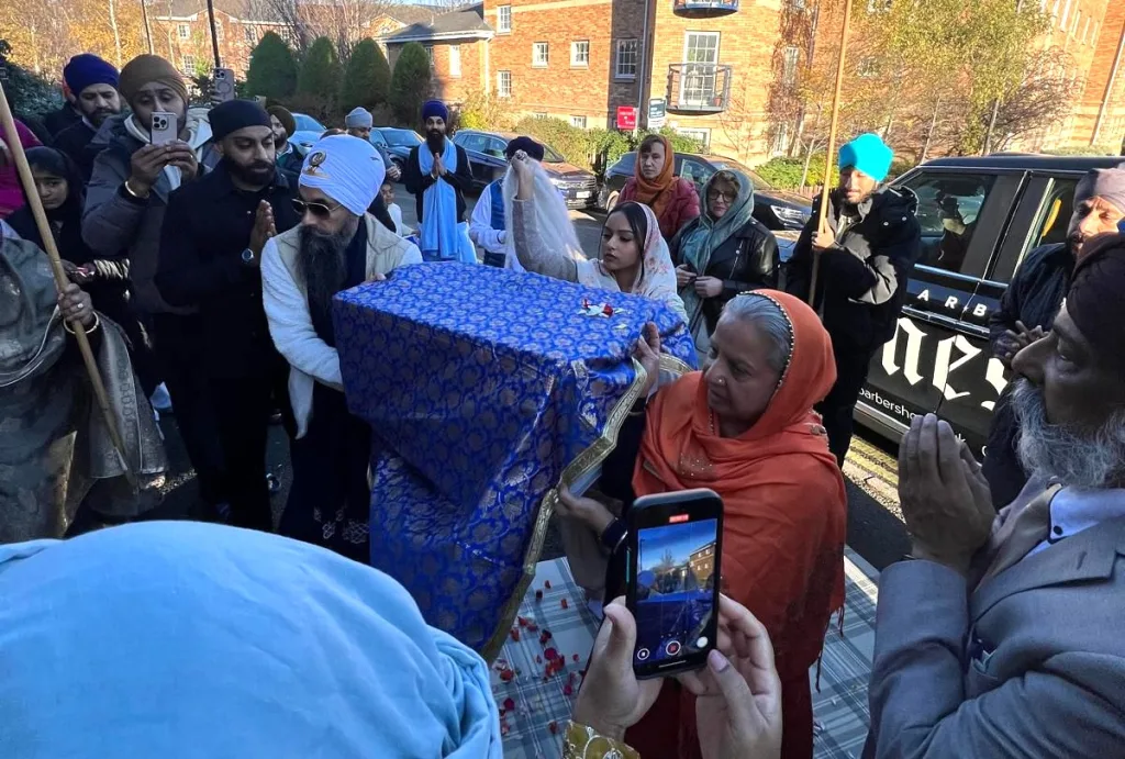 Trishna Singh OBE and Dharamveer Singh Khalsa carrying the Guru Granth Sahib into Edinburgh Gurdwara.