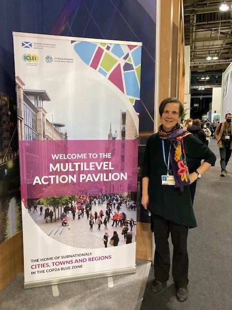 Professor Elizabeth Bomberg standing next to a banner which reads Welcome to the Multilevel Action Pavilion