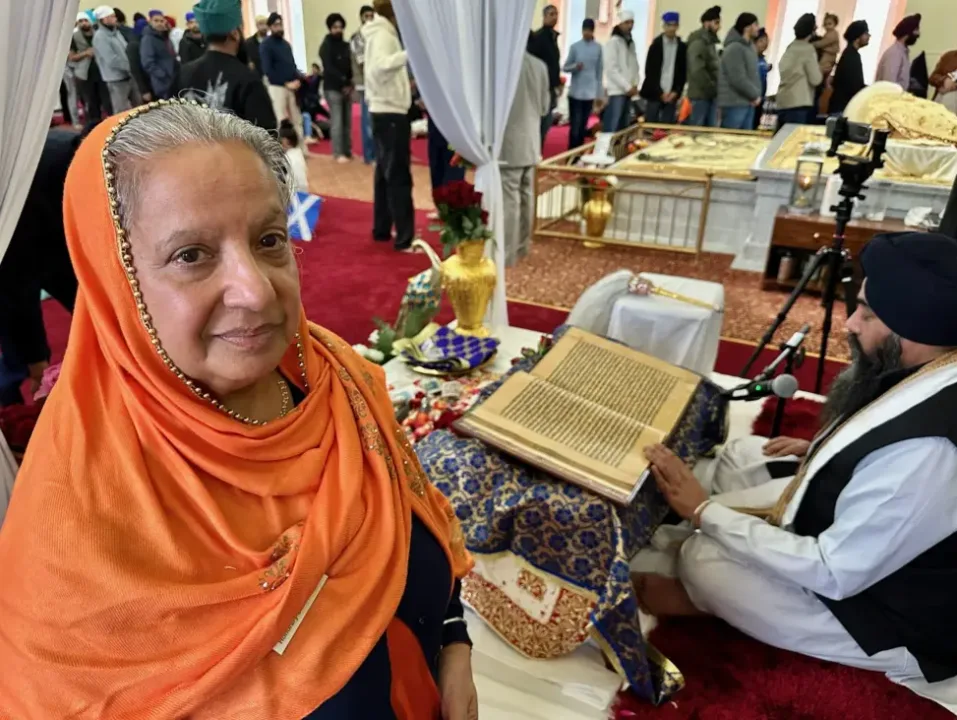 Trishna Singh next to the Guru Granth Sahib in Edinburgh Gurdwara.