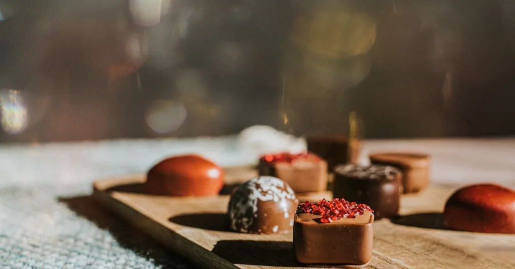 A variety of chocolates sitting on a wooden tray
