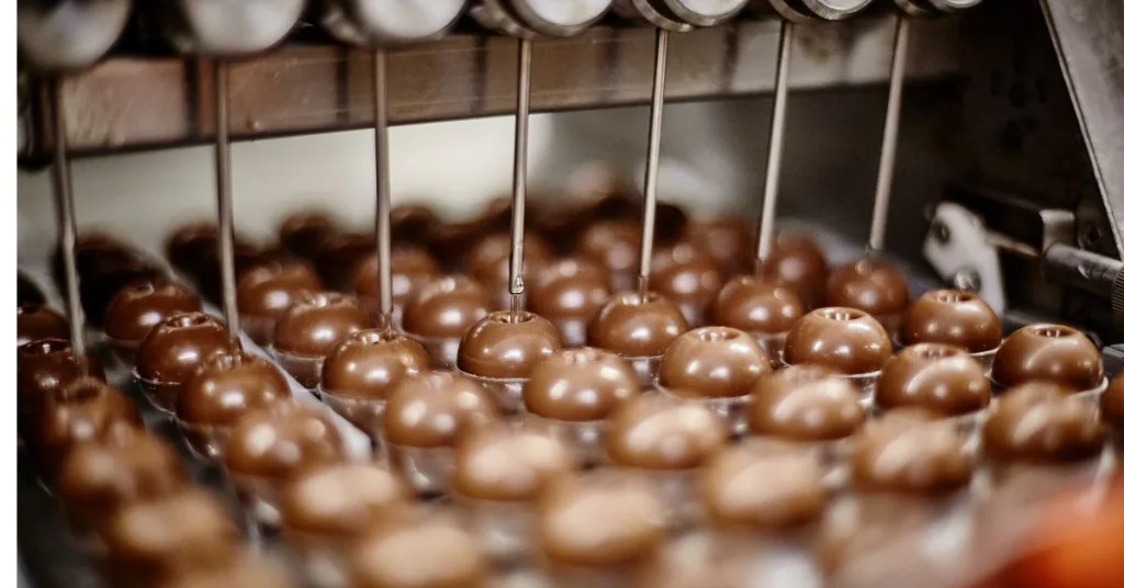 A machine filling round chocolate moulds with liquid