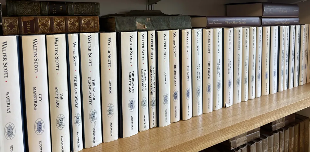 A photograph displaying twenty seven spines of books on a bookshelf. Each book is by Walter Scott and reflects the number of his novels that Dr McKeever read during the pandemic by this author. The image illustrates the volume of work produced by Walter Scott.