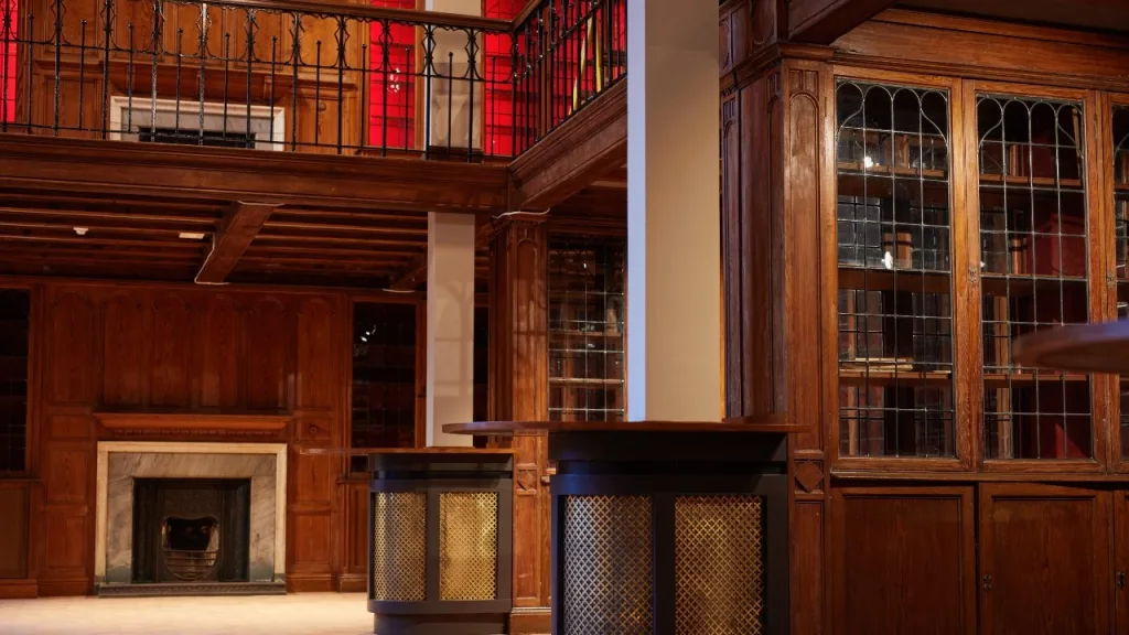 An interior view of the Library Bar, featuring wood paneling, a fire place and original bookcases. 