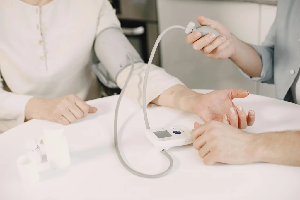 A patient and a doctor sitting at a table with a blood pressure monitor