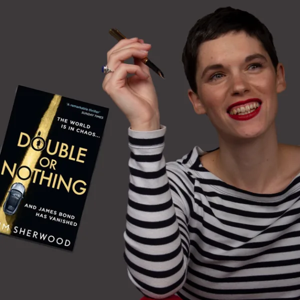 Kim Sherwood posing with two of her books: A Spy Like Me and Double or Nothing.