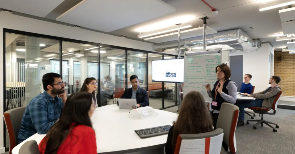 Students sitting around a table looking at a whiteboard