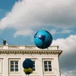 A balloon shaped like earth floating above a building
