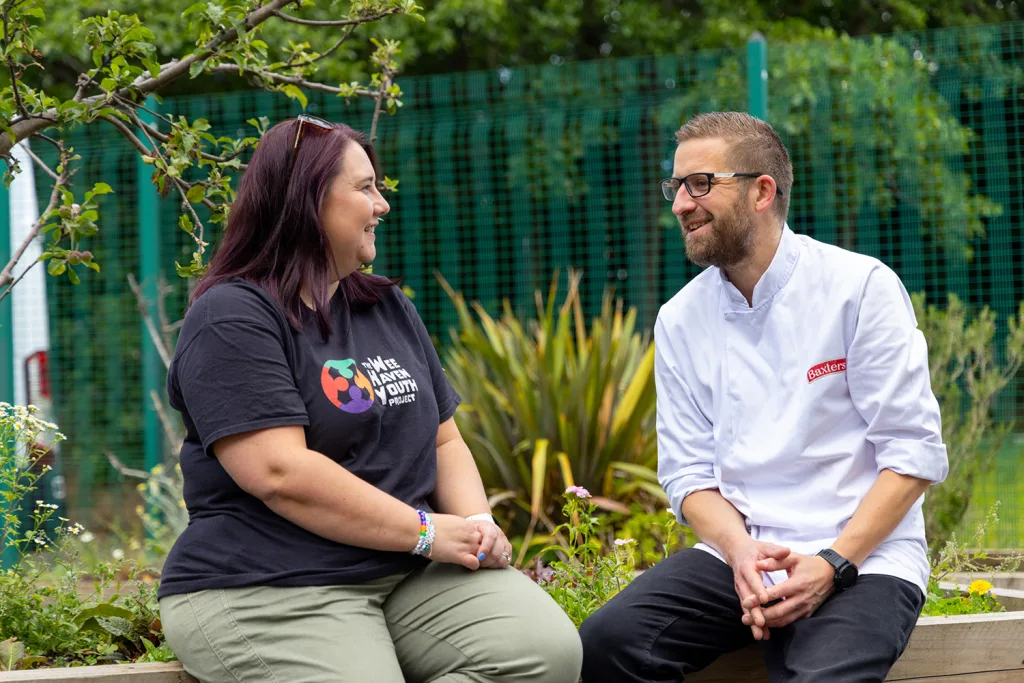 Sabrina sitting outside chatting with a chef from Baxters, one of The WHY Projects's funding partners.