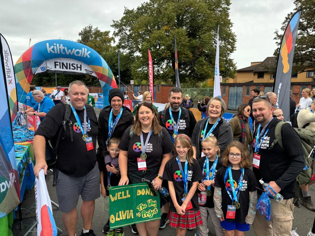 Sabrina and fellow team and young people wearing meddles at the finish line after taking part in a Kiltwalk to raise funds for their youth work.
