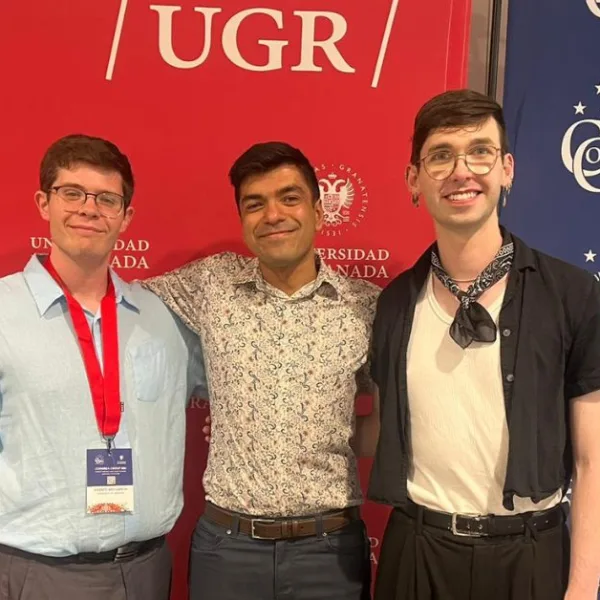 Three people with their arms round each other and smiling at the camera