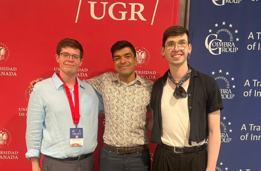 Three people with their arms round each other and smiling at the camera