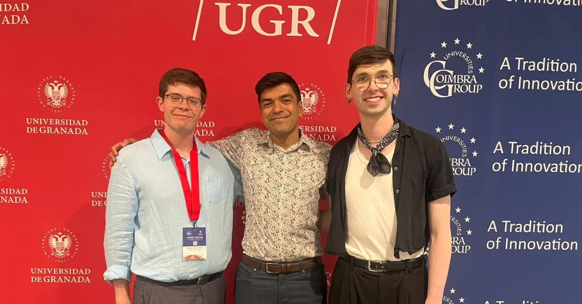 Three people with their arms round each other and smiling at the camera