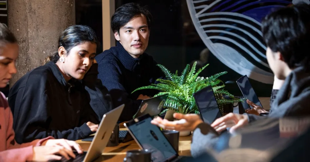 A group of students sitting at a table with their laptops